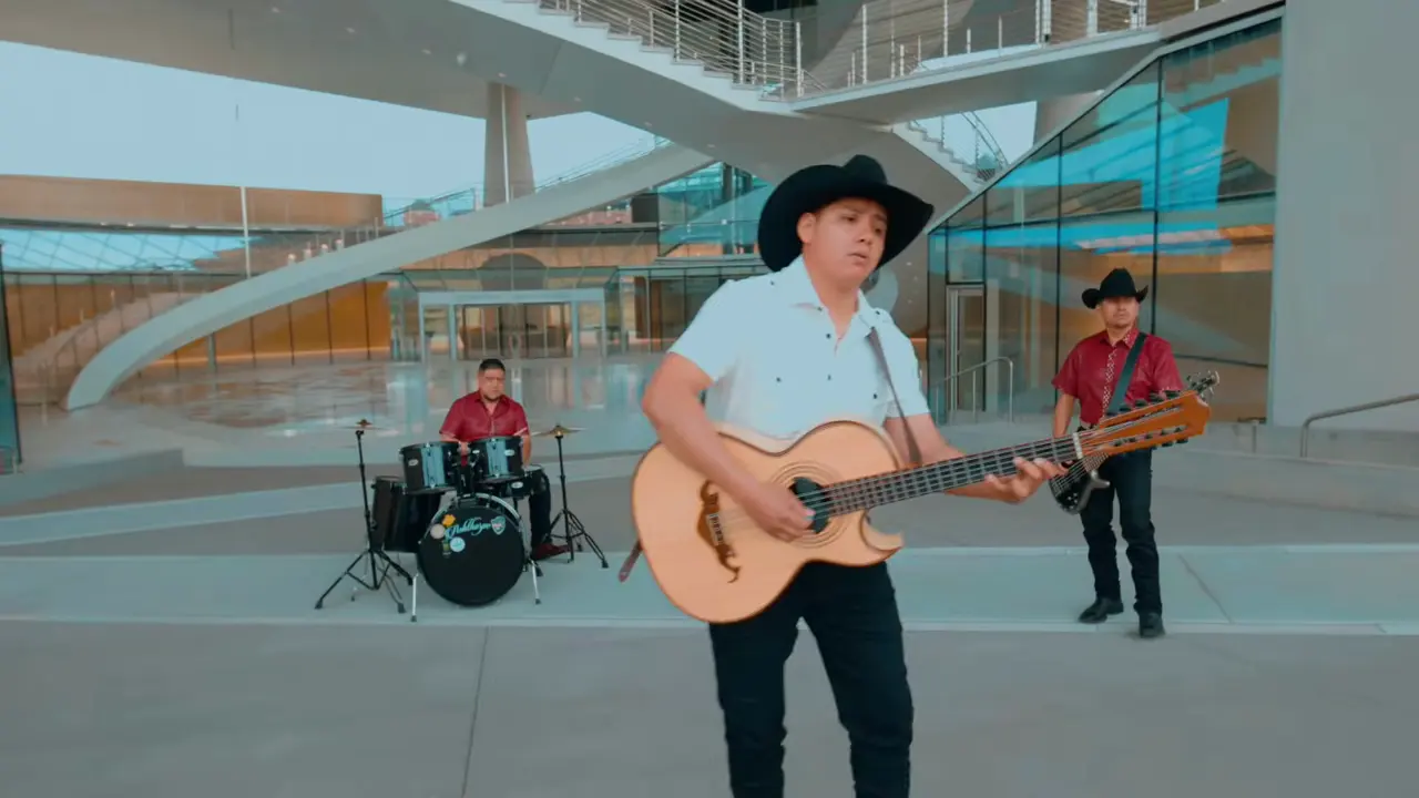 El vocalista de Estado Norteño con su bajo quinto y el grupo al fondo